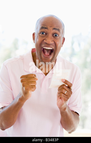 Homme avec ticket de loterie excité et smiling Banque D'Images