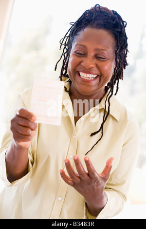 Femme avec ticket de loterie excité et smiling Banque D'Images