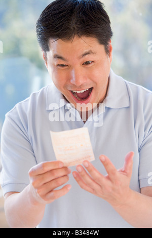 Homme avec ticket de loterie excité et smiling Banque D'Images