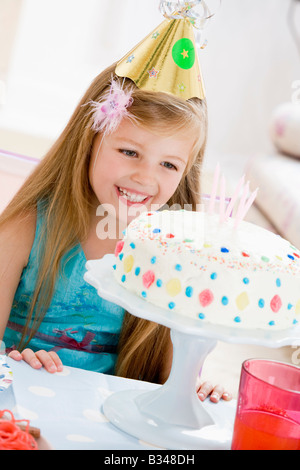 Young Girl wearing party hat and smiling cake Banque D'Images