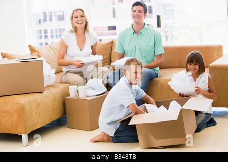 Family unpacking boxes in new home smiling Banque D'Images