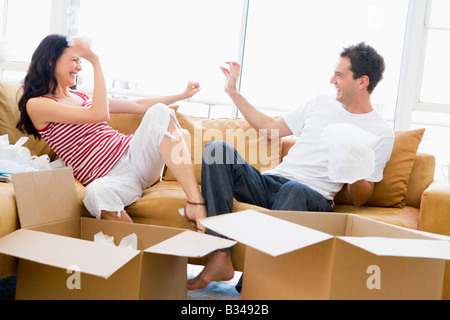 Par espièglerie couple unpacking boxes in new home smiling Banque D'Images
