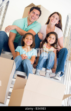 Family sitting on staircase avec boxes in new home smiling Banque D'Images