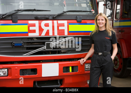 Firewoman standing in front of fire engine Banque D'Images