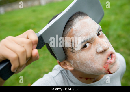 Jeune garçon avec Scary Halloween maquillage et tête de couteau en plastique Banque D'Images