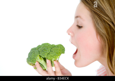 Teenage girl eating broccoli Banque D'Images