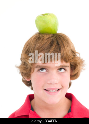 Jeune garçon avec pomme sur la tête en souriant Banque D'Images