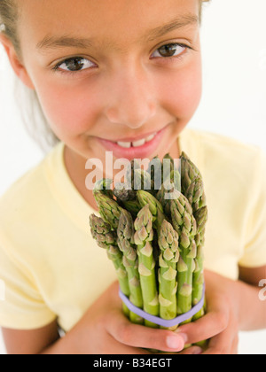 Young Girl holding bunch of asparagus and smiling Banque D'Images