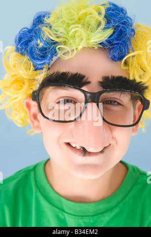 Jeune garçon portant perruque et faux nez de clown smiling Banque D'Images