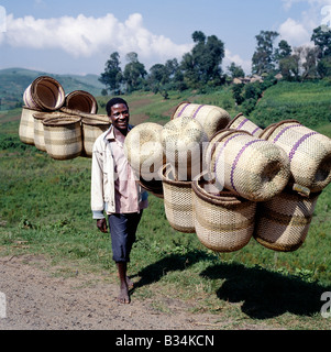 L'Ouganda, le sud-ouest de l'Ouganda, Muko. Un homme porte les paniers de bambou en duplex à vendre à Kisoro marché. La plupart des femmes dans le sud-ouest de l'Ouganda s'acquitter de leurs produits au marché agricole dans ces beaux paniers en équilibre sur leur tête. La vannerie est l'apanage des hommes. Banque D'Images