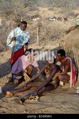 Kenya, Samburu, South Horr. Une jeunesse Samburu assis sur un boeuf cacher juste après qu'il a été circoncis à l'extérieur de sa mère Banque D'Images