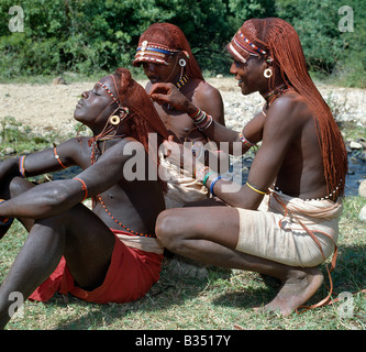 Le Kenya, l'Horr, Kurungu. Deux guerriers Samburu robe les tresses d'un collègue. Longues tresses de cheveux Ochred. Banque D'Images