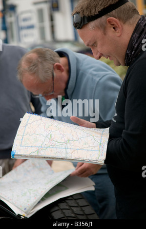 2 deux hommes se plonger dans des atlas routier Grande-Bretagne la planification de l'itinéraire de leur voyage en voiture - N'utilisez pas sat nav pour les guider Banque D'Images