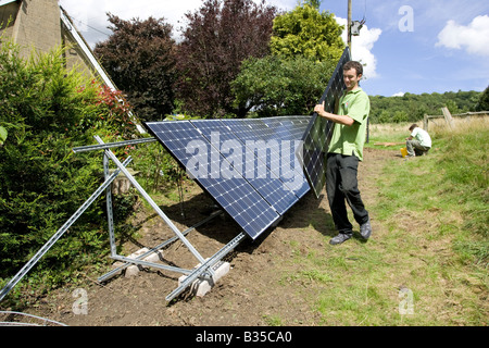 L'installation de travailleurs à panelson PV solaire dans un cadre galvanisé UK Cotswolds terrain Banque D'Images