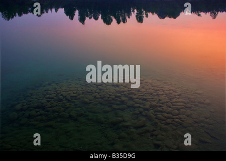 Un tas de pierres immergées dans les eaux de la rivière Po dépeinte au coucher du soleil avec les couleurs chaudes du coucher de soleil reflété Banque D'Images