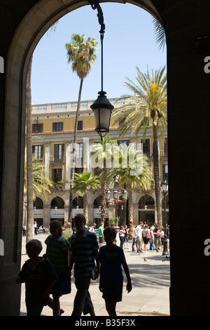 Espagne Barcelone Silhouette de quatre personnes marchant à travers arch palmiers et fontaine en plaça Reial en arrière-plan Banque D'Images