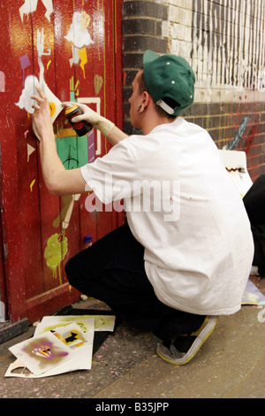 Artiste de rue à l'aide de pochoirs et de peinture en aérosol à Banksy's 2008 Cans Festival à Londres, Leake Street Banque D'Images