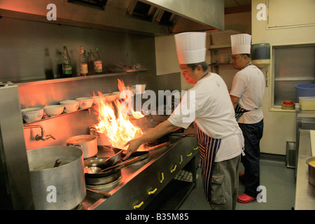 Cuisine Chef Thaï mâle avec flaming wok dans un restaurant Cuisine, Cuisine orientale Banque D'Images