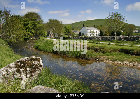 Malham Beck qui passe Malham, et cottage avec des roches calcaires dans l'avant-plan - North Yorkshire Dales National Park Banque D'Images