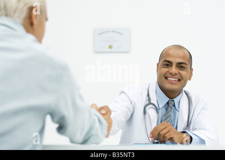 Doctor shaking hands with patient, smiling at camera, portrait Banque D'Images