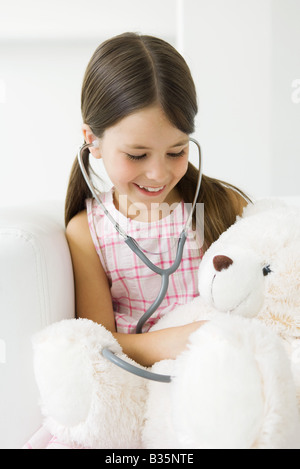 Jeune fille à l'écoute de Teddy's bear's heart with stethoscope Banque D'Images