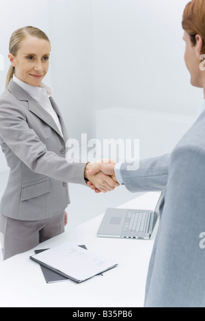 Businesswoman shaking hands with portrait de l'homme à tête rouge Banque D'Images
