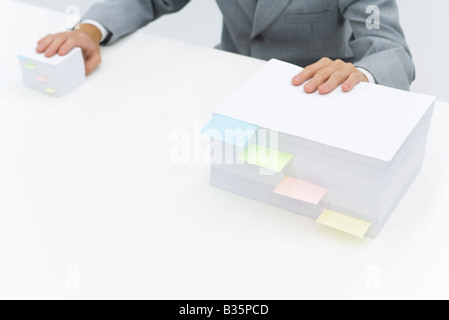 Piles de papier avec des notes adhésives en les divisant, l'homme en mettant une main sur chaque pile Banque D'Images
