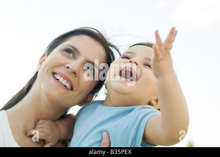 Mother holding baby, les deux looking up and smiling Banque D'Images