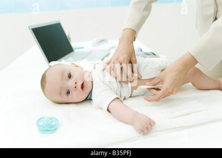 Mère de changer la couche de bébé sur 24, un ordinateur portable en arrière-plan, Portrait Banque D'Images