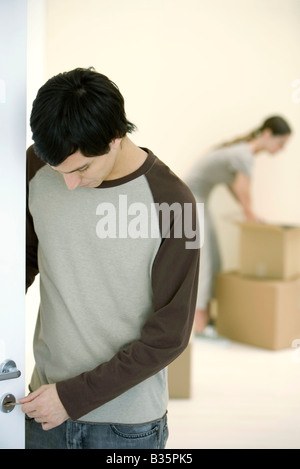 Essais sur l'homme clé de la serrure de porte, woman unpacking boxes in background Banque D'Images