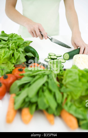 Woman slicing concombre, légumes variés en premier plan, Portrait Banque D'Images