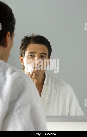 L'homme d'appliquer la crème à raser, se voir dans le miroir Banque D'Images