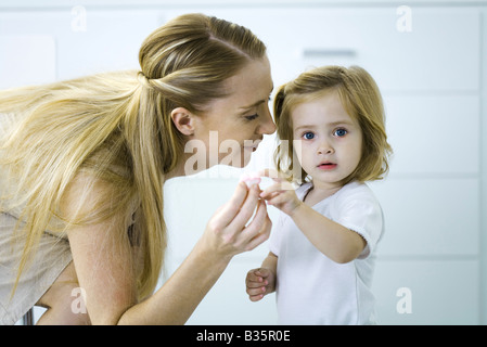 Petite fille en donnant sa mère un tout petit coeur, looking at camera Banque D'Images