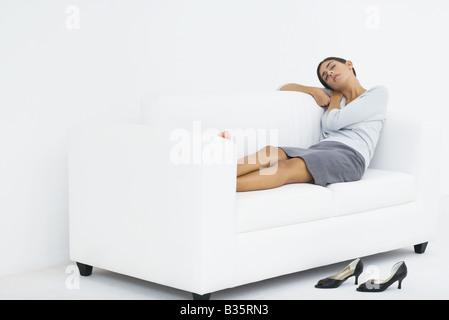 Femme couchée sur la table, la tête reposant sur ses bras, les yeux fermés Banque D'Images