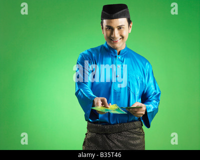 Malay man giving out duit raya Banque D'Images