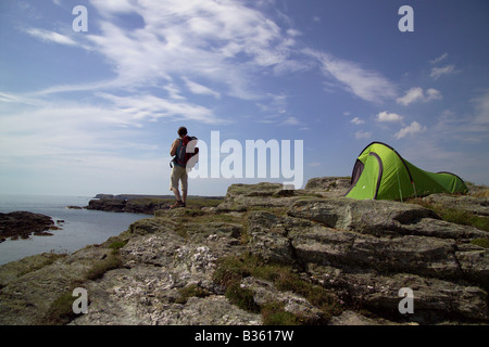 Walker et tente verte sur la falaise surplombant la mer. Banque D'Images