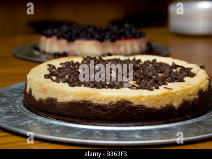 Un gâteau au fromage au chocolat sur une assiette de couleur argent avec un gâteau aux bleuets en arrière-plan. New York, USA. Banque D'Images