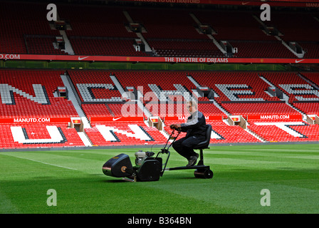 Un groundsman de couper le gazon à Old Trafford, domicile du club de football Manchester United, Manchester, Angleterre, Royaume-Uni Banque D'Images