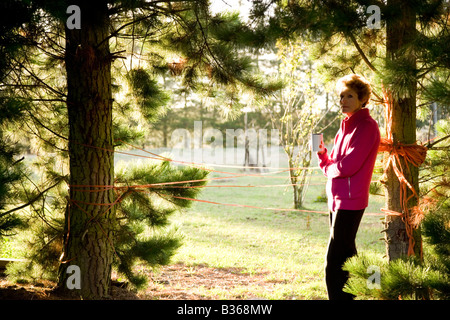 Mature Woman holding mug à l'ombre d'arbre Banque D'Images