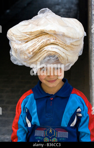 République Boy carrying Pain frais sur sa tête dans la vieille ville d'Alep en Syrie Banque D'Images