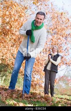 Ramasser des feuilles à l'extérieur de l'homme et la femme en arrière-plan smiling (selective focus) Banque D'Images