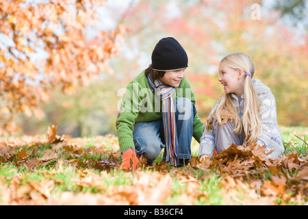 Deux jeunes enfants à l'extérieur du parc en jouant dans les feuilles et smiling (selective focus) Banque D'Images