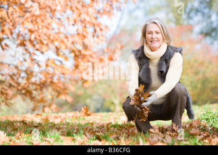 Woman outdoors holding feuilles et smiling (selective focus) Banque D'Images