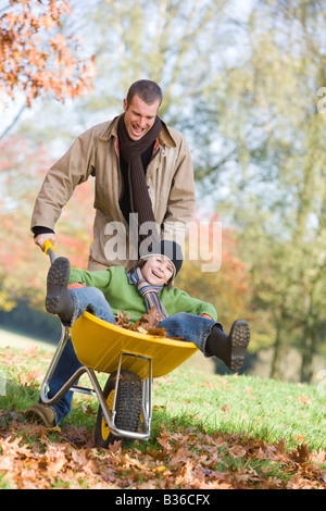 L'homme et jeune garçon à l'extérieur jouer avec brouette et smiling (selective focus) Banque D'Images