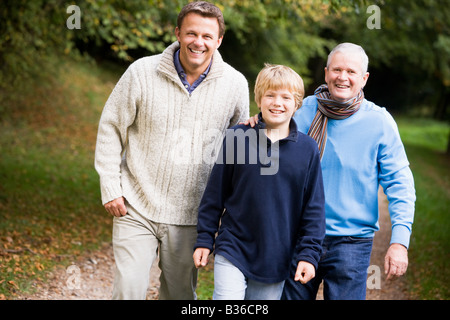 Deux hommes et jeunes boy walking on path outdoors smiling (selective focus) Banque D'Images