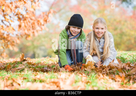 Deux jeunes enfants en plein air au parc et jouent dans les feuilles et smiling (selective focus) Banque D'Images