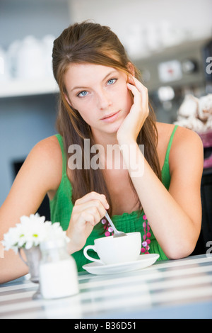 Jeune femme assise à une table, boire du thé Banque D'Images