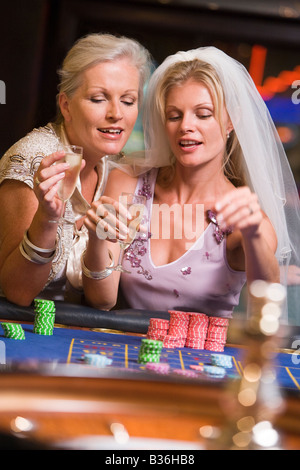 Femme au voile de la mariée avec une autre femme au casino jouer à la roulette et smiling (selective focus) Banque D'Images