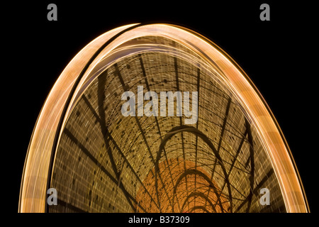 Mouvement giratoire et coloré motif créé par l'éclairage de l'animation, capturés lors d'une longue exposition de cette grande roue. Banque D'Images