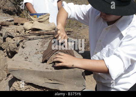 Apprendre à faire le toit de tuiles demi-rondes un jeune garçon fait sa marque dans l'argile humide, Chirche, Guia de Isora, Tenerife Banque D'Images